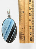 Making Waves Jewelry and Accessories oval banded agate pendant in sterling silver next to a wooden ruler for scale