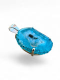 Making Waves Jewelry and Accessories blue druzy agate pendant in a sterling silver prong setting on white background.