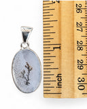 Making Waves Jewelry and Accessories oval dendritic agate pendant in sterling silver next to a wooden ruler for scale