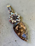 Making Waves Jewelry and Accessories teardrop fossil coral pendant with a silver floral bail on a grey background.