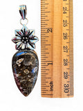 Making Waves Jewelry and Accessories fossil coral teardrop pendant with a silver floral bail next to a wooden ruler.