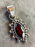 Making Waves Jewelry and Accessories marquise-cut garnet pendant in beaded sterling silver with a high-polish finish.