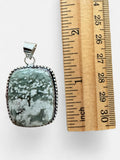 Making Waves Jewelry and Accessories handcrafted sterling silver pendant with a green patterned gemstone and beaded edge.