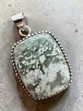 Making Waves Jewelry and Accessories handcrafted sterling silver pendant with a mossy green patterned gemstone.
