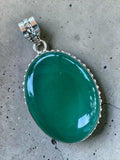 Making Waves Jewelry and Accessories oval green onyx pendant with beaded sterling silver setting on concrete background