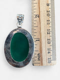 Making Waves Jewelry and Accessories oval green onyx pendant in sterling silver with beaded edge next to a ruler