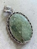 Making Waves Jewelry and Accessories oval green rutilated quartz pendant in an ornate vintage sterling silver setting.