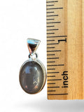 Making Waves Jewelry and Accessories oval grey moonstone pendant in a sterling silver setting next to a ruler