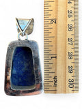 Making Waves Jewelry and Accessories handcrafted Lapis Lazuli pendant in sterling silver next to a wooden ruler