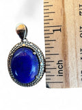 Making Waves Jewelry and Accessories oval lapis lazuli pendant with a beaded sterling silver frame next to a ruler.