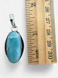 Making Waves Jewelry and Accessories oval Larimar pendant in 925 sterling silver next to a wooden ruler for scale