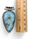 Making Waves Jewelry and Accessories teardrop Larimar pendant with silver filigree setting next to a wooden ruler.
