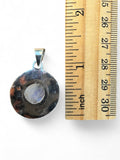 Making Waves Jewelry and Accessories round moonstone pendant with silver-tone frame next to a wooden ruler for scale