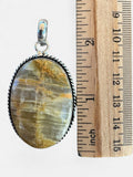Making Waves Jewelry and Accessories oval gemstone pendant with golden-brown inclusions in a silver rope-style frame