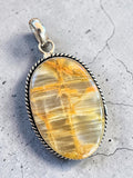 Making Waves Jewelry and Accessories oval gemstone pendant with golden-brown inclusions and a twisted silver rope border