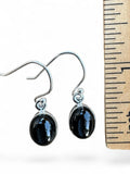 Making Waves Jewelry and Accessories oval black star diopside drop earrings in sterling silver next to a ruler.