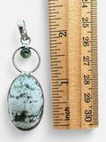 Making Waves Jewelry and Accessories oval stone pendant with green accent stone and sterling silver setting by a ruler