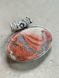 Making Waves Jewelry and Accessories oval stone pendant with terracotta, cream, and grey patterns in a silver setting.
