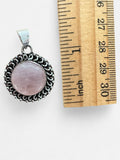 Making Waves Jewelry and Accessories round rose quartz pendant in an ornate sterling silver setting next to a ruler.