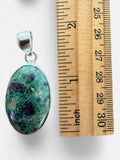 Making Waves Jewelry and Accessories oval ruby in fuchsite pendant set in sterling silver next to a ruler