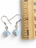 Making Waves Jewelry and Accessories square moonstone dangle earrings in sterling silver next to a wooden ruler.