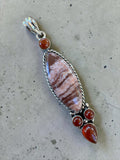 Making Waves Jewelry and Accessories artisan pendant with patterned stone, twisted silver, and red carnelian accents.