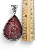 Making Waves Jewelry and Accessories teardrop Crazy Lace Agate pendant with silver filigree bail next to a ruler.