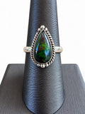 Making Waves Jewelry and Accessories teardrop Ammolite ring in sterling silver with rope detailing on a display stand
