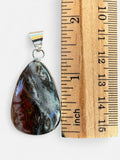 Making Waves Jewelry and Accessories teardrop gemstone pendant in sterling silver bezel next to a wooden ruler