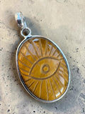 Making Waves Jewelry and Accessories oval Tiger's Eye pendant with a carved evil eye motif in sterling silver setting.